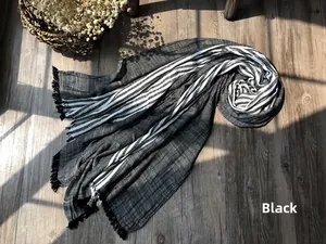 Detailed close-up of striped cotton scarf with fringe on a rustic wooden floor