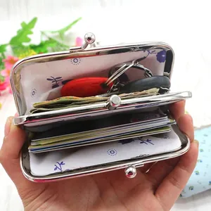 Handheld view of a blue floral canvas coin purse with a double-layer metal kiss lock