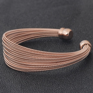 Detail of rose gold braided cable wire cuff bracelet featuring smooth spherical end caps