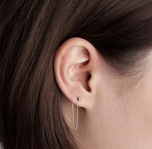 Detail of minimalist 925 silver bead stud earring with a hanging metal tassel chain