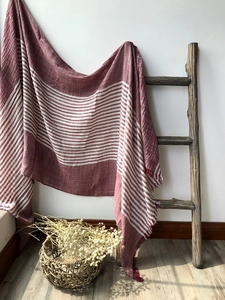 Detail of red and white striped cotton scarf with fringe on a rustic wooden ladder