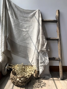 Close-up of striped cotton scarf with fringe hanging on a vintage wooden ladder