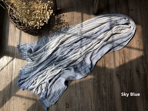 Close-up of light blue striped cotton scarf with fringed edges on dark wood