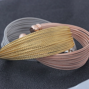 Detail of three twisted cable bracelets in gold silver and rose gold finishes