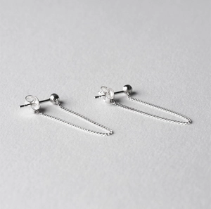 Detail of minimalist 925 sterling silver ball stud earrings with delicate chain tassels