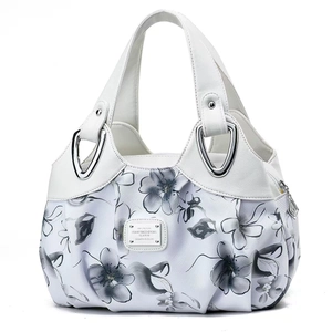 Detail of white leather handbag featuring grey floral fabric and silver metal hardware