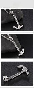 Macro detail of silver stainless steel hammer pendant with engraved text and cable chain