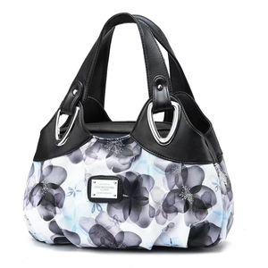 Close-up of printed fabric handbag with silver metal rings and black leather straps