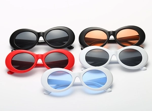 Flat lay of retro oval sunglasses in black, white and red frames with colored lenses