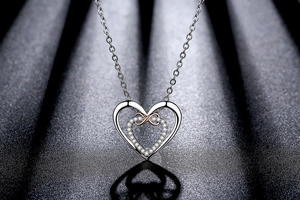 Macro detail of silver heart necklace with rose gold infinity pendant and small diamonds