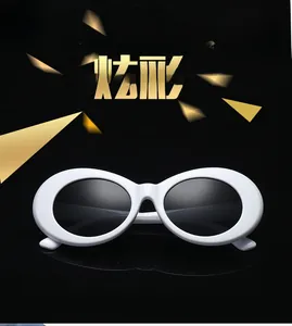 Detail shot of vintage white oval sunglasses with dark lenses on a black reflective surface