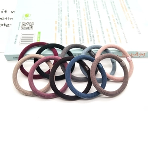 Durable flocked seamless hair ties in 10 diverse colors stacked on a white book
