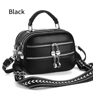 Detail of black pebbled leather crossbody bag with three zippers and patterned wide strap