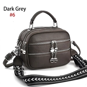 Detail of dark grey textured crossbody bag with three zip compartments and woven strap