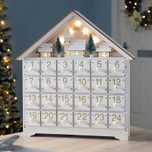 Detail of wooden advent calendar house with 24 numbered drawers and illuminated top scene