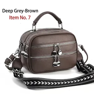 Detail view of large dark taupe shoulder bag featuring triple zippers and woven strap