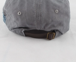 Detail of gray washed cotton cap with vintage faux leather strap and bronze metal buckle