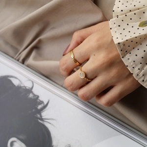 Close-up of vintage gold rings set featuring opal-like stone on a hand model