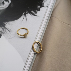 Detail of gold-plated two-piece ring set with cat's eye stone and braided rope texture