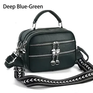 Dark green pebbled leather handbag with multiple zipper pockets and wide patterned strap