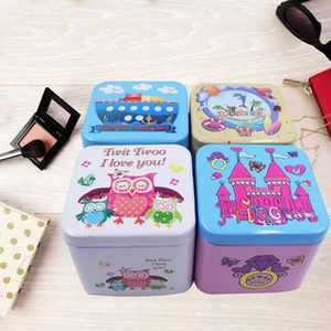 Close-up of square cartoon tin storage boxes on wood background for organizing accessories