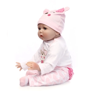 Realistic reborn baby doll in pink animal ear hat and heart pattern outfit sitting on white