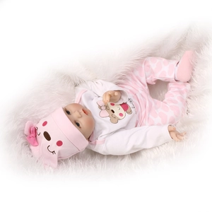 Detail of 40cm realistic baby doll wearing a pink bear outfit on a soft white plush rug