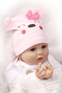 Close-up of lifelike baby doll with blue eyes and pink bow hat on white faux fur