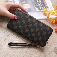 Close-up of ethnic long zipper wallet with classic floral embroidery on brown fabric