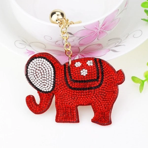 Detailed view of a red crystal elephant keychain with gold chain on a porcelain cup