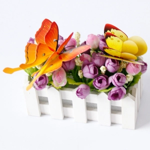 Close-up of artificial red roses and colorful double-layer butterfly wall stickers in a fence