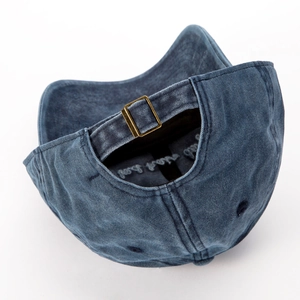 Detalle de la hebilla metálica ajustable en una gorra de béisbol lavada y desgastada