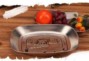 Detail of vintage silver boat-shaped tin tray with rural house embossed pattern