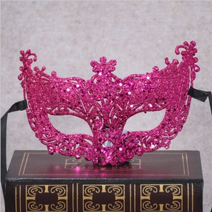 Rose red Venetian masquerade mask with pink glitter on a vintage decorative book
