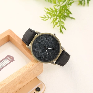 Denim dial bronze watch with black strap on minimalist textured desktop background