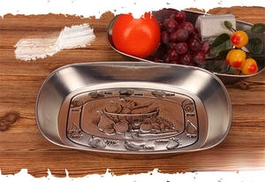 Detailed close-up of fruit embossed patterns on the vintage oval stainless steel tray