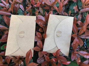 Detailed view of brown kraft paper envelopes with creative heart-shaped clasps on leaves
