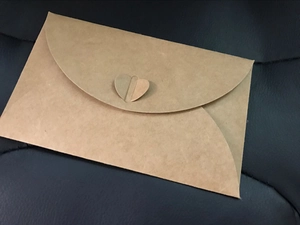 Detailed close-up of brown kraft paper envelope featuring a unique heart-shaped closure