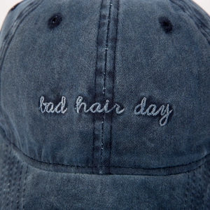 Primer plano de gorra de béisbol de mezclilla azul con bordado "bad hair day".