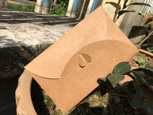 Macro detail of natural kraft paper envelope featuring a unique heart-shaped closure design