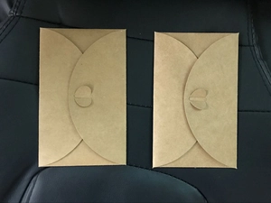Detail of two brown kraft paper envelopes with heart-shaped clasps on dark background