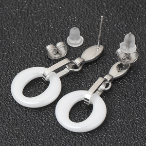 Macro shot of white ceramic round rings with silver stainless steel earring findings