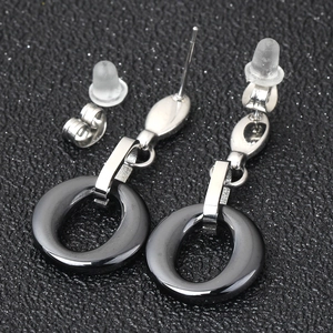 Detailed close-up of silver earrings with black ceramic rings and two types of backings