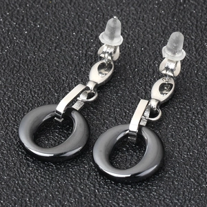 Close-up of black ceramic hoop earrings with silver metal connectors and silicone backs