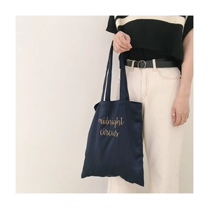 Detail of navy blue canvas tote bag with golden midnight circus embroidery for daily use