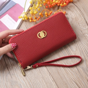 Close-up of red lychee textured leather wallet with gold hardware and wrist strap