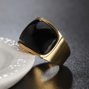 Anello minimalista in titanio dorato con grande pietra nera su porcellana bianca