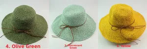 Close-up of summer raffia hats in grass green, mint green, and yellow with leather bows