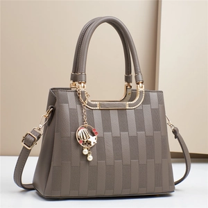Detail of grey crossbody bag with square embossed texture and elegant shell charm