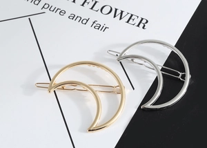 Close-up of minimalist gold and silver hollow moon hair clips with polished finish